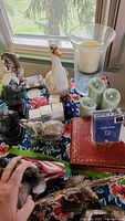 Photo of entire lot showing dog bookends, wolf figurine with orb, acrylic photo frames, glass candle holder, coasters, light-up goose, flameless candles, decorated photo book box, silver-tone wooden elephant and light-up flower.