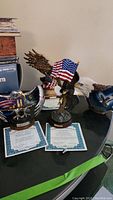 Photo of three Bradford Exchange patriotic eagle figurines on a black table, with two Certificates of Authenticity in front