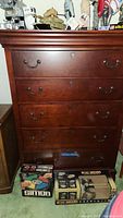Front view of Broyhill five drawer dresser showing metal handles, reddish wood finish, and overall condition with some dings.