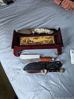 Full set of three knives/daggers on a cloth surface, artisan knife lies on its decorative stand.