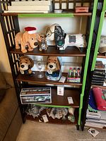 Shelving unit with stuffed animals, Grinch ornament, decorative shells, and boxed Hess toy set