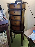 Full view of the wooden jewelry chest showing its five drawers with metal pulls and curved legs.