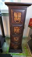 Photo of tall narrow wooden media cabinet with four drawers and metal ring pulls
