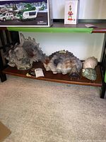 Front view of the large seashell decor including the spiked shell and clam-like shell, arranged on a wooden shelf below a glass tabletop.