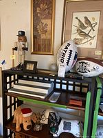 Wide shot of shelf with signed Patriots football, Super Bowl football, Yankees nutcracker and baseball bat along with miscellaneous items.