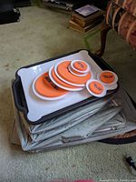 Multiple orange and white circular moving sliders in different sizes on top of plastic trays resting on fabric storage bags.