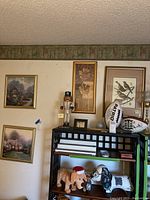 Overview showing three framed art pieces hanging on wall, including the bird illustration on the right and floral piece in the center.