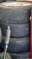 Close-up photo of stacked tires with heavy tread wear and visible sidewall marks.