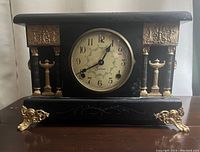 Front view of the antique Seth Thomas mantel pillar clock on a wooden surface.