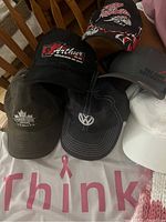 Photo showing six ball caps with various logos including Volkswagen, Indian Motorcycles, and Arthur brand.