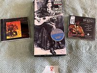 Three blues music CDs laid out on a surface: Robert Johnson complete recordings box set, BB King Essentials CD, and another blues CD with a group photo on the cover.