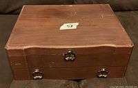 Closed wooden chest with two metal handles and sticker showing lot number 58