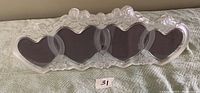 Front view of the clear crystal frame showing four heart-shaped openings with dark photo backing and decorative edges.