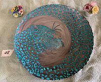 Top view of large circular glass plate with blue leopard design and silver background, flanked by two small china flower arrangements.