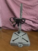 Front row showing metal base with diagonal adjustment slots and vertical support post with Dremel clamp mount and adjustment knobs.