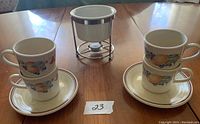 Photo showing fondue pot flanked by two stacked cups on their saucers on each side, all with Corelle Abundance fruit pattern.