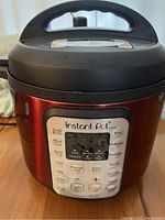 Front view of Instant Pot Viva with control panel visible, red color with black lid and handle.