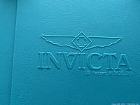 Close-up of Invicta logo embossed on turquoise hard plastic case interior lid.