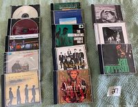 15 Music CDs of various artists arranged on green fabric, showing front cover artwork for identification.