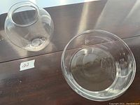 Crystal vase and clear crystal bowl sitting side by side on a wooden table, showing shape and transparency.