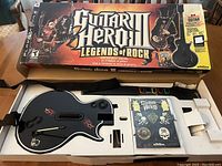 Guitar Hero III Legends of Rock box partially open revealing wireless guitar controller and game case inside