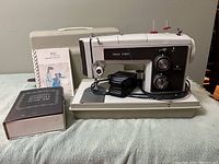 Kenmore sewing machine with hard carrying case and instruction manuals on display