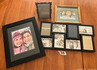 Showcasing the three frames included in the lot: large multi-photo black hanging frame, small pewter standing frame, and black framed photo.