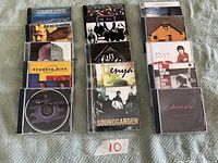 Photo showing 15 music CDs arranged on fabric, covers visible including North Sound, Ian Tyson, The Cult, Enya, Soundgarden, Depeche Mode and others.