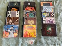 Photo showing 20 CD albums from various artists laid out in four rows on a green fabric surface, with album covers visible including Hanson, No Doubt, Dave Matthews Band and others.