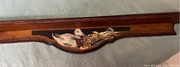 Close-up detail of carved and painted duck design on wooden shelf