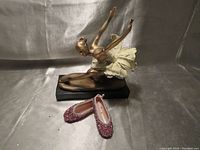 Ballerina figurine and pink toe slippers set nicely displayed on grey background.