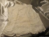 Top laid flat on satin fabric showing full front and hemline beadwork detail.