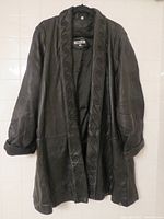 Front view of black leather jacket showing the overall style and scrolling detailing along front edges and collar area.