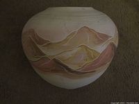 Image of a round ceramic vase with a cream base and hand painted mountain scenery in pink and brown tones.