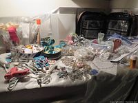 Photo showing collection of hobby and craft items laid out on a table including beads, charms, butterfly figurines, scissors, and organizer bag.