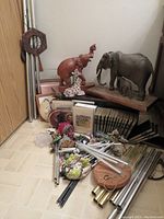 Overall view of lot including plywood box, animal statues, metal wind chimes, and vintage books on floor