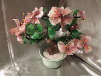 Full view of vintage Chinese bonsai floral tree in celadon pot with pink flowers and green leaves made from jade, quartz, stone, and glass.