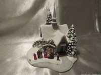 Wide shot of the snowy winter church with nativity scene and surrounding trees on a glittered base.