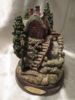 Front view of the Thomas Kinkade Sweetheart Cottage II music box sculpture showing house, stone steps, lantern, and waterfall.