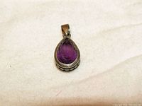 Close-up image of a vintage faceted amethyst tear drop pendant set in 925 sterling silver, showing the purple gemstone and silver openwork edge detail.