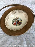 Top view of antique serving dish showcasing central classical scene painting inside with gold patterning around inner edge and gold rim