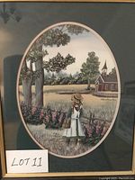 Framed oval lithograph depicting a girl with a hat in a field with a church and trees in the background.