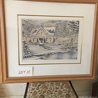 Framed print of winter scene with house, snow-covered trees, and pond with mat and light wood frame, labeled as Lot 15.