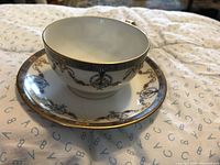 Photo of tea cup and saucer showing blue and pink floral garland pattern with gold trim on porcelain.