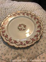A single vintage Limoges dessert plate showing floral design around scalloped edges, central floral wreath, and gold trim.
