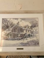 Framed print showing a wintery country store scene with detailed architecture and landscape.