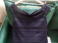 Front view of navy blue off-the-shoulder Ted Baker dress laid flat showing horizontal banded design.