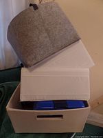 Stack of miscellaneous storage containers with blue lunch box partially visible inside.