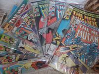 Stack of 11 The New Mutants comic books in plastic sleeves fanned out showing colorful Marvel comic covers from early 1980s.