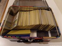 Photo of the interior of a metal Pokemon trading card tin filled with many cards arranged vertically.